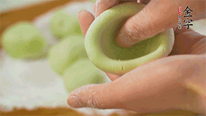 將均分的艾草面團搓成圓，挖一個窩，放入餡心，再搓成圓。