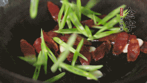 先后下香腸片、四季豆絲均勻翻炒，加適量清水燜煮一下。