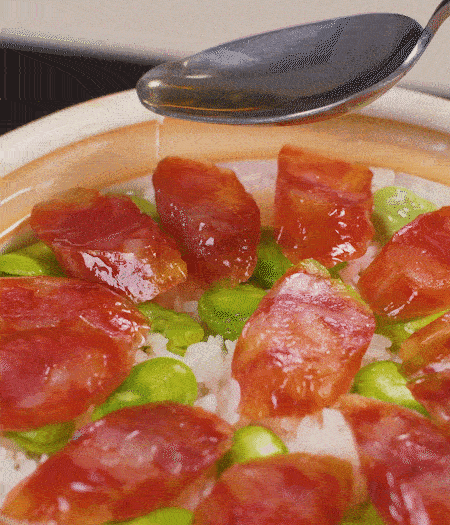 大米出現(xiàn)小孔時開蓋放香腸，往鍋邊淋入少許油，再燜煮8~10分鐘左右。