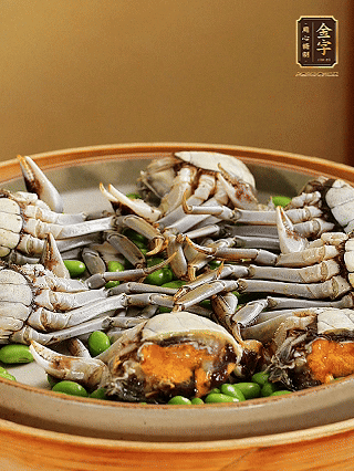 盤(pán)底鋪毛豆，依次放大閘蟹、咸肉， 淋一圈料酒、豉油。